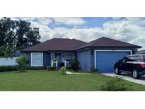 Charming single-story home with a well-maintained lawn, blue paint, and a cozy front porch at 455 Eagle Dr, Kissimmee, FL 34759