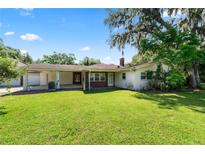 Spacious backyard featuring lush green grass, mature trees, and an attached carport for convenient parking at 5425 Lewellyn Rd, Lakeland, FL 33810