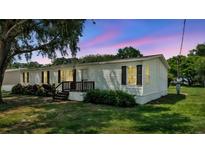 Charming single-story home with white siding, black shutters, front porch, and mature trees on a green lawn at 5751 Cherry Tree Dr, Lakeland, FL 33811