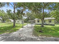 Charming fenced property featuring a single-story home, green lawn, and gravel driveway, all surrounded by mature trees at 633 Glenda St, Lakeland, FL 33805