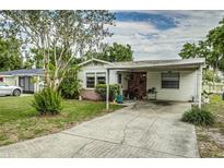 Charming single-story home with a covered carport, inviting front yard and beautiful landscaping at 102 Pike St, Auburndale, FL 33823