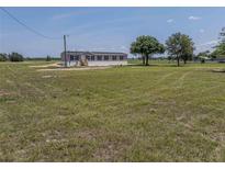 Single-story home featuring neutral siding, black shutters, and a large, grassy yard at 246 Quail Run, Frostproof, FL 33843
