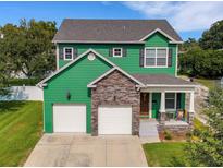 Inviting two-story green home featuring a stone facade, covered porch, and an attached two-car garage at 2731 Coventry Ave, Lakeland, FL 33803
