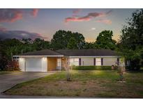 Charming single-story home featuring a well-maintained lawn and attached garage, set against a colorful twilight sky at 2757 Pine Acres Dr, Lake Wales, FL 33898