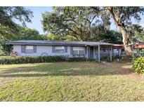 Charming single-story home featuring a covered porch, mature trees, and a well-manicured lawn at 2920 Audie Combee Rd, Lakeland, FL 33801