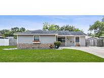 Charming single-story home showcasing a well-manicured lawn and gray facade with stone accents at 417 El Salvador Dr, Lakeland, FL 33809