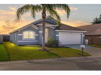 Charming single-story home with a well-manicured lawn and mature palm tree set against a colorful sunset sky at 436 Lady Diana Dr, Davenport, FL 33837