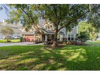 Traditional-style home featuring a lush lawn and a large mature tree shading the front at 4808 Juliana Reserve Dr, Auburndale, FL 33823