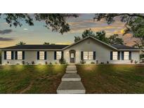 Charming single-story home with white siding, blue shutters, a manicured lawn, and a concrete walkway at 4825 Foxrun, Lakeland, FL 33813