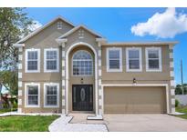Charming two-story home with a manicured lawn and a two-car garage, featuring a classic architectural design at 5163 Spanish Oaks Dr, Lakeland, FL 33805