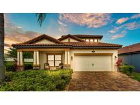 Inviting single-story home with well-manicured landscaping, a brick driveway, and a two-car garage at 1902 Altavista Cir, Lakeland, FL 33810