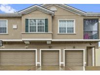 A tan townhouse showcasing three garage doors and a window with shutters at 2061 Crestdale Ln # 60, Lake Mary, FL 32746