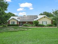Charming single-story home with solar panels, manicured lawn, brick accents, and lush landscaping at 2921 W Socrum Loop Rd, Lakeland, FL 33810