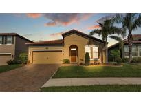 Charming single-story home featuring a well-manicured lawn, brick driveway, and a terracotta tiled roof at 4088 Prima Lago Cir, Lakeland, FL 33810
