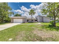 Charming single-story home with a well-manicured lawn, mature trees, and an attached two-car garage at 6338 Oak E Sq, Lakeland, FL 33813