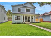 Charming two-story home with a well-manicured lawn, covered porch, and light-blue siding at 727 S Missouri Ave, Lakeland, FL 33815