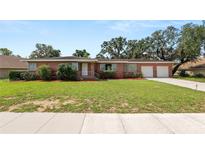 Charming single-story brick home featuring a well-maintained front lawn and an attached two-car garage at 111 E Orange St, Davenport, FL 33837