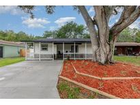 Charming one-story home with a welcoming porch and landscaped front yard featuring a beautiful mature shade tree at 113 Patrick Henry Rd, Bartow, FL 33830