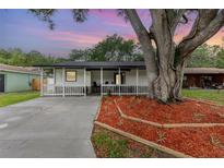 Charming one-story home with a welcoming porch and landscaped front yard featuring a beautiful mature shade tree at 113 Patrick Henry Rd, Bartow, FL 33830