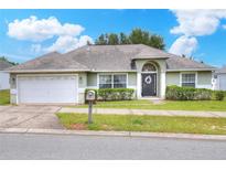 Charming single-story home featuring a two-car garage, well-maintained lawn, and decorative front door wreath at 1140 Stratton Ave, Groveland, FL 34736