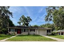 Charming single-story home featuring a red front door, well-maintained lawn, and an attached one-car garage at 1215 E Edgewood Dr, Lakeland, FL 33803