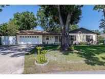 Charming single-story home featuring an attached garage and a well-maintained lawn with mature trees at 1434 Country Ridge Dr, Lakeland, FL 33801