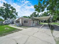 Single-story home with a carport, a truck and a small storage shed in the background at 2120 Dille St, Lakeland, FL 33815