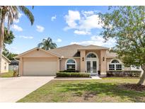 Charming single-story home featuring a manicured lawn, arched windows, and a welcoming double-door entrance at 3568 Jade Ln, Mulberry, FL 33860