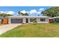 Charming single-story home featuring a new metal roof, gray garage door and beautiful landscaping at 416 Bayou Rd, Winter Haven, FL 33884