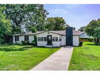 Charming single-story home with white exterior, black trim, chimney, and lush green lawn at 4629 Harden Blvd, Lakeland, FL 33813
