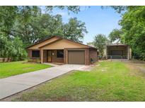 Cozy one-story brick home featuring an attached garage, long driveway and a detached, gated carport for additional covered parking at 5120 Lunn Rd, Lakeland, FL 33811