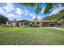 Ranch style home with a red metal roof, a covered car port, and a well-maintained lawn at 5140 Alderman Rd, Lakeland, FL 33810