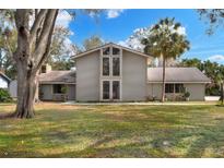 Charming two-story home boasts a large front yard, palm tree, and unique architectural details at 1118 Cypress W Pt, Winter Haven, FL 33884