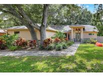 Charming single-story home with a beautifully landscaped front yard, mature trees, and inviting walkway at 1300 Ariana Woods Cir, Auburndale, FL 33823