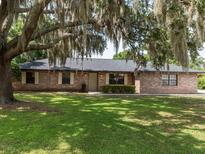 Charming single-story brick home featuring lush green lawn and mature tree with Spanish moss at 1315 Costine Dr, Lakeland, FL 33809