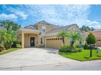 Charming home featuring a two-car garage, a well-manicured lawn, and lush landscaping with palm trees at 1739 Laurel Glen Pl, Lakeland, FL 33803