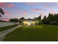 Charming single-story home featuring a well-maintained lawn and mature landscaping during a colorful sunset at 1820 Salem Rd, Lakeland, FL 33803