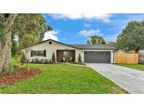 Charming single-story home with a gray roof, wood accents, a long driveway, and green grass at 1920 Kimball S Ct, Lakeland, FL 33813