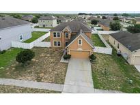 Aerial view of tan two-story home in a residential neighborhood with fenced yards at 2170 Forest Lake Ave, Dundee, FL 33838