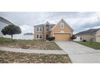 Two-story home with tan exterior, attached garage, and simple landscaping on an overcast day at 2170 Forest Lake Ave, Dundee, FL 33838