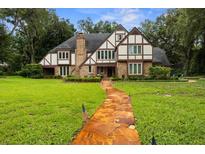 Charming Tudor-style home with a brick facade, lush green lawn, and a stone pathway leading to the front door at 6001 Sweet Gum Run, Bartow, FL 33830