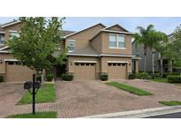 Inviting two-story townhome with a paver driveway, manicured landscaping, and an attached two-car garage at 6415 Torrington Cir, Lakeland, FL 33811