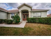 Charming home featuring a red double-door entry and well-maintained front yard landscaping with flower accents at 8323 Greystone Dr, Lakeland, FL 33810