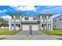 Modern two-story duplex featuring a paver driveway, private balconies, and manicured lawn at 1172 Windjammer Dr, Lakeland, FL 33803