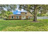 Charming two-story brick home with blue shutters and lush front yard shaded by mature trees at 1910 Clubhouse Rd, Lakeland, FL 33813