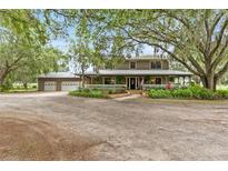 Charming two-story home with a wraparound porch, lush landscaping and detached three car garage at 2911 Walker Rd, Lakeland, FL 33810