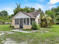 Quaint single-story home featuring a screened front porch and mature landscaping at 320 W Carver St, Lakeland, FL 33805