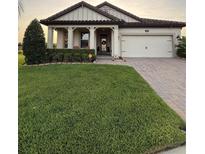 Inviting single-story home featuring a well-manicured lawn and a charming brick-paved driveway and walkway at 4124 Prima Lago Cir, Lakeland, FL 33810