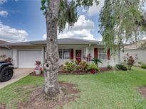 Charming home exterior with lush landscaping, red shutters, and well-maintained lawn at 4926 Pleasant Hollow Trl, Lakeland, FL 33811