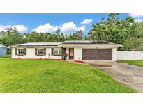 Charming single-story home with a well-maintained lawn, a two-car garage, and modern solar panels at 5316 Forestbrook E Dr, Lakeland, FL 33811